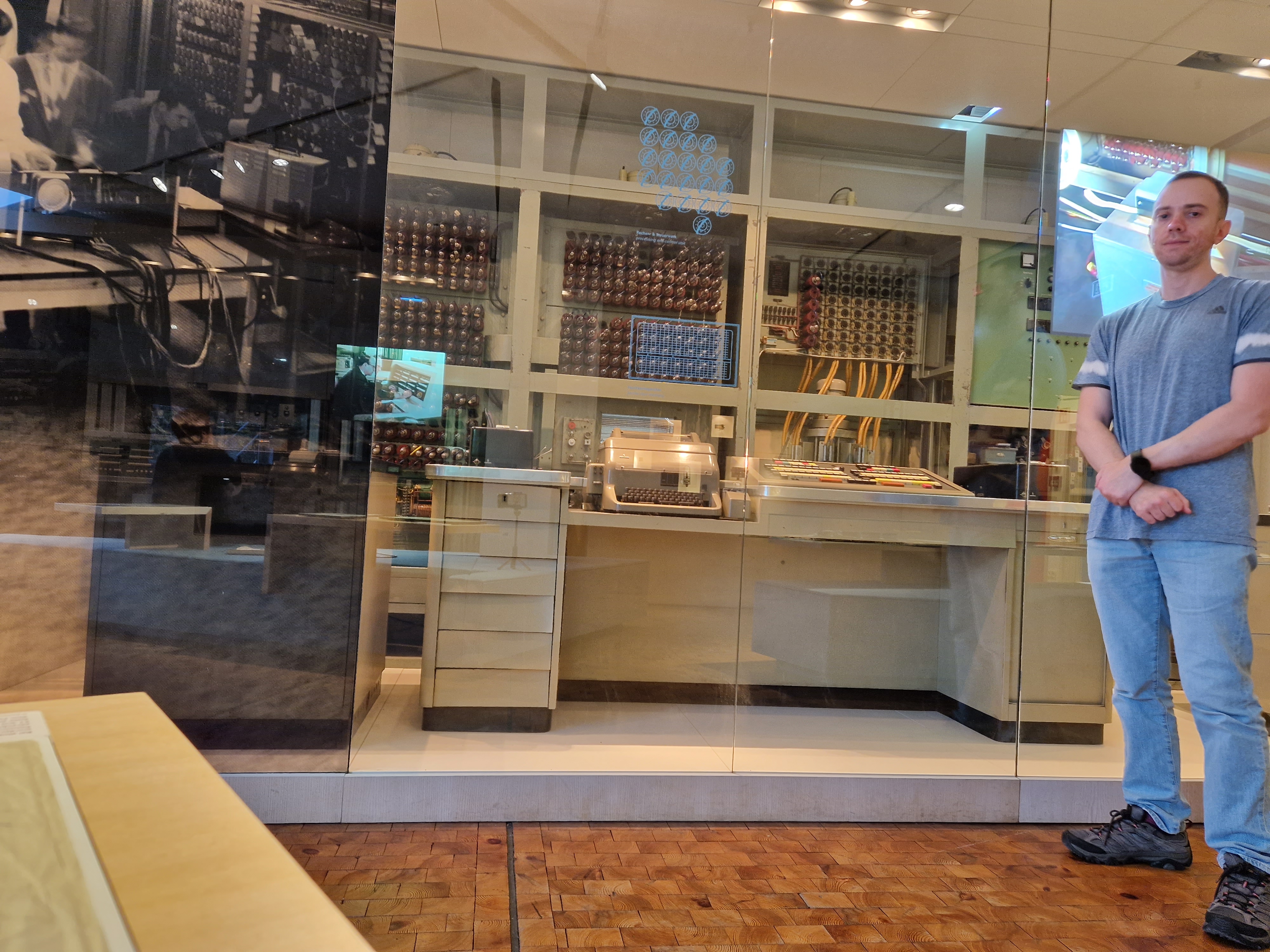 Dany Trakhtenberg standing next to the Zuse Z25 computer at a computing history museum in Germany